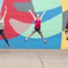 A still from the documentary short Oak Street Mural where three people are jumping in front of the mural.