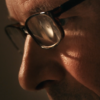 A closeup of Steven Valleau working with glasses on from Madeleine Cohen’s documentary Bird Carver.