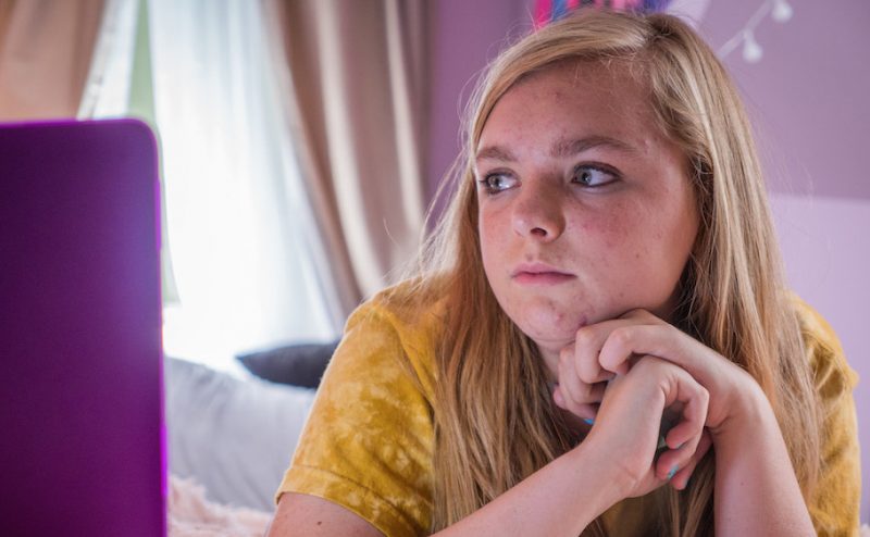 Elsie Fisher with her head on her hands looking longingly at a computer screen in Bo Burnham's Eighth Grade, the opening night film at IFFBoston 2018.
